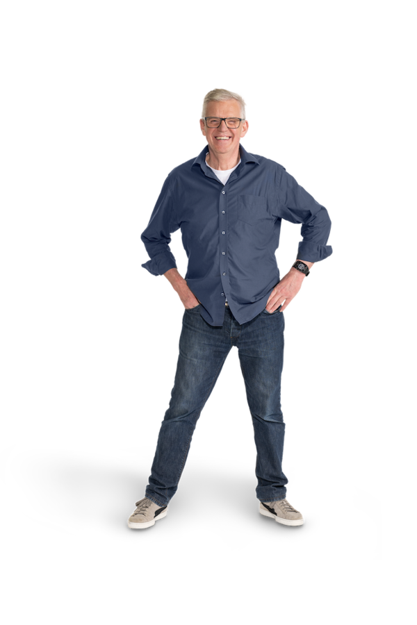 Ein älterer Mann mit grauem Haar, Brille, Jeanshose und Jeanshemd.