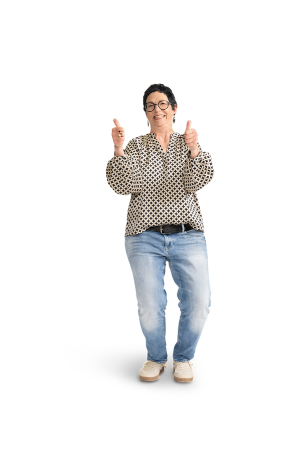 Eine Frau mir kurzen, schwarzen Haaren, Brille, gemusterter Bluse und Jeans.
